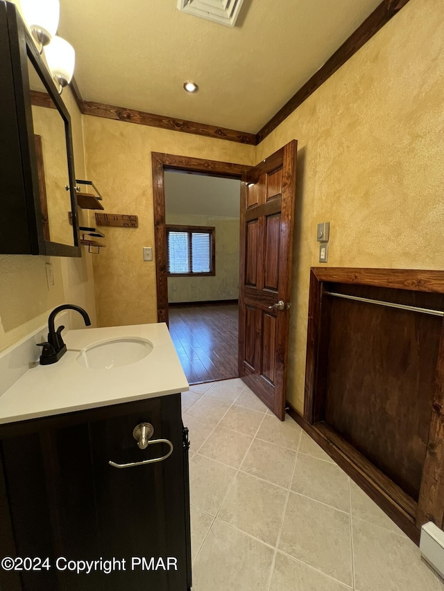 bathroom with visible vents, a textured wall, ornamental molding, vanity, and tile patterned floors