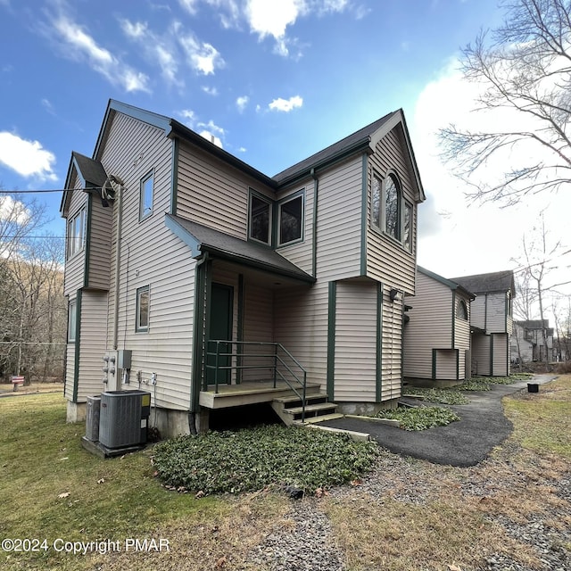 rear view of property featuring central AC and a yard