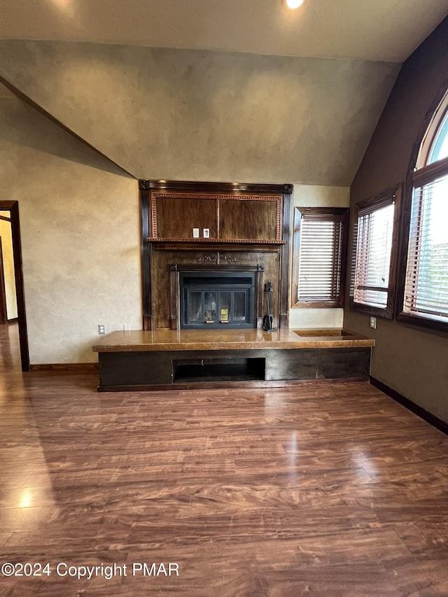 unfurnished living room featuring vaulted ceiling, baseboards, and wood finished floors