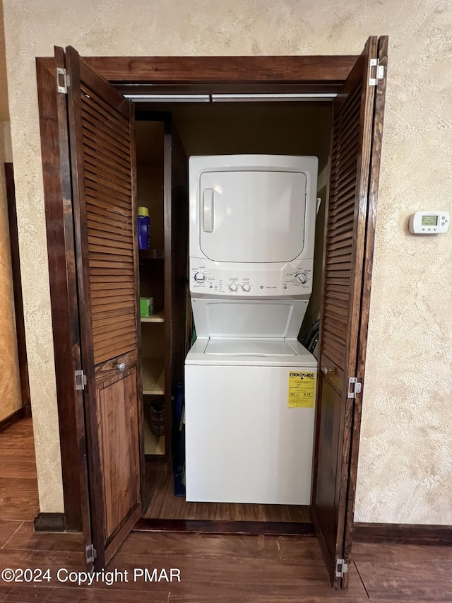 clothes washing area with stacked washer and dryer, wood finished floors, and laundry area