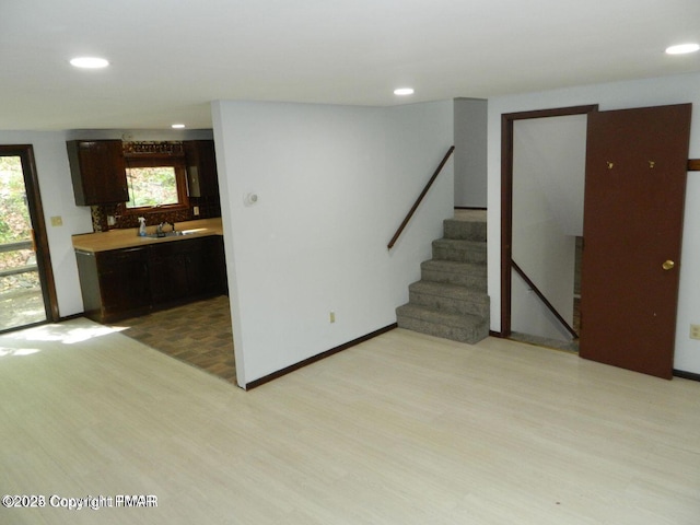 interior space featuring a sink, dark brown cabinets, light wood finished floors, and light countertops