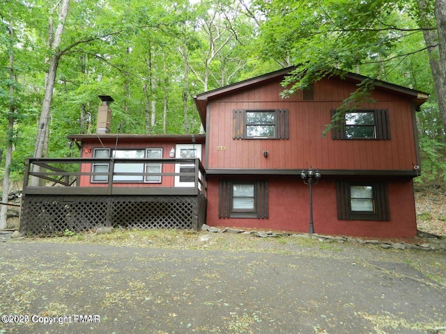 rear view of house with a chimney and a wooden deck