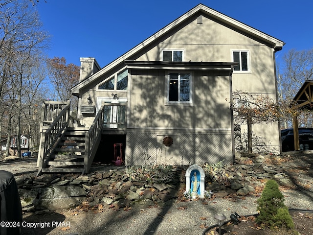 view of property exterior featuring stairway, a chimney, and a deck