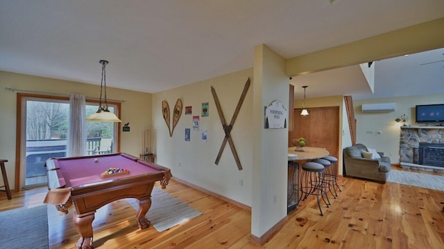 playroom featuring a fireplace, an AC wall unit, pool table, baseboards, and light wood-type flooring