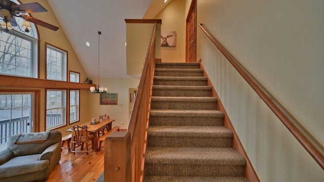 stairway with an inviting chandelier, high vaulted ceiling, recessed lighting, and wood finished floors