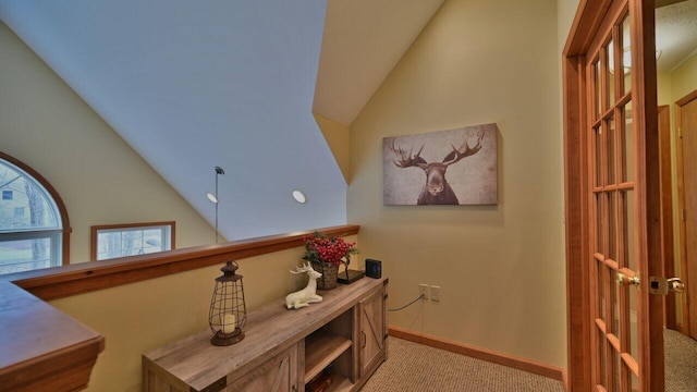 hall with baseboards, light carpet, and high vaulted ceiling