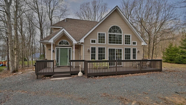 rustic home featuring a wooden deck and roof with shingles