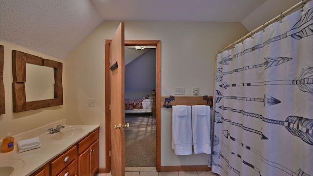 ensuite bathroom with a sink, double vanity, a textured ceiling, ensuite bathroom, and lofted ceiling