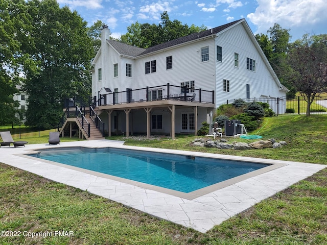 back of property with a deck, stairway, and a lawn