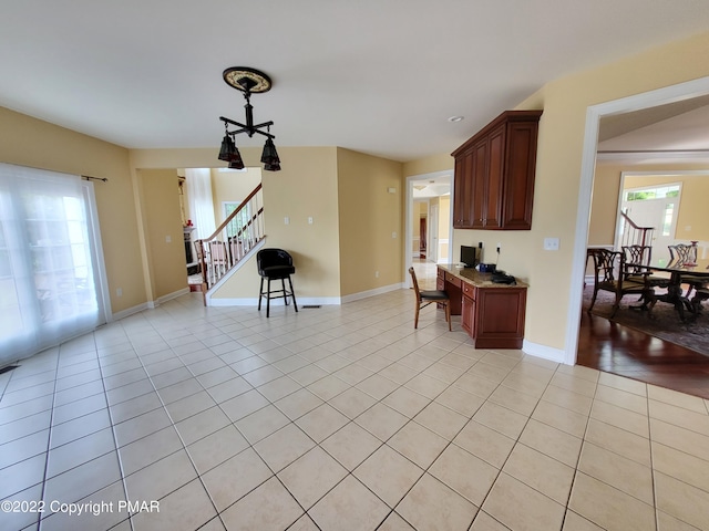 kitchen featuring light tile patterned floors, hanging light fixtures, and baseboards