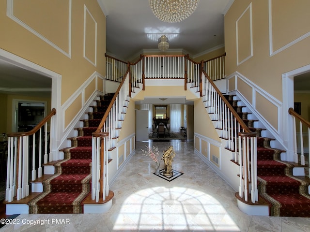 entryway with ornamental molding, stairway, a towering ceiling, and a decorative wall