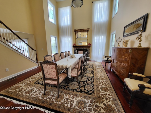 dining room featuring a towering ceiling, wood finished floors, and visible vents