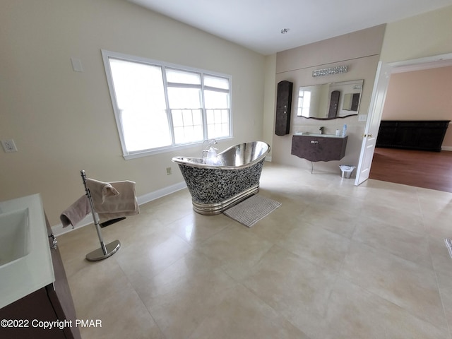 interior space with a soaking tub, vanity, and baseboards