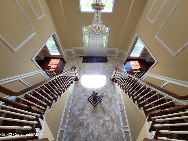 foyer featuring stairs, a towering ceiling, and an inviting chandelier