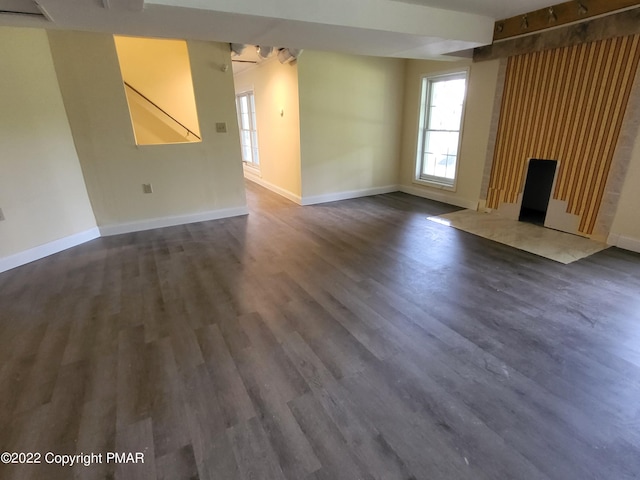 unfurnished living room featuring baseboards, dark wood-style flooring, and a high end fireplace