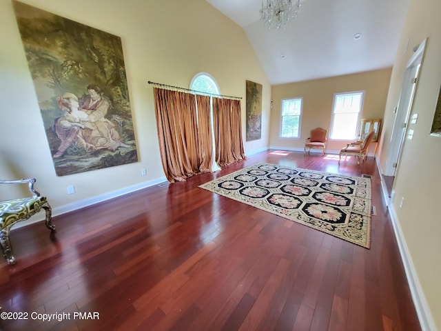 living room featuring baseboards, high vaulted ceiling, wood-type flooring, and a notable chandelier