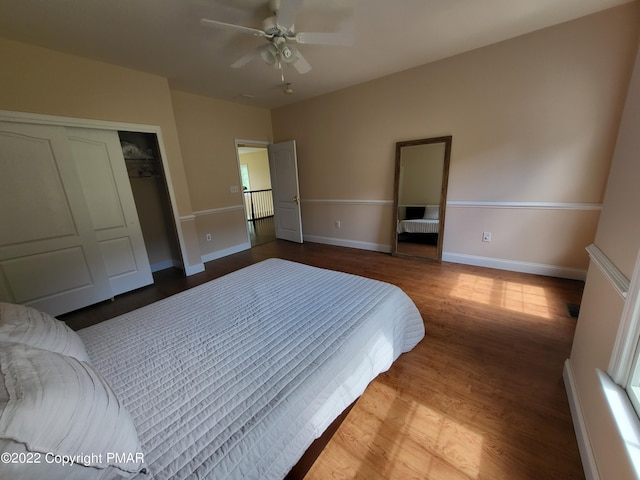 bedroom featuring a closet, ceiling fan, baseboards, and wood finished floors