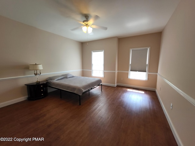 unfurnished bedroom with dark wood-type flooring, baseboards, and a ceiling fan