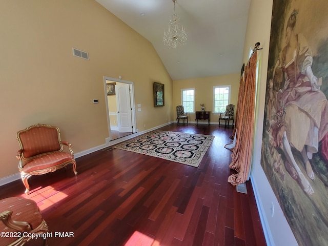 foyer entrance with baseboards, visible vents, a chandelier, wood finished floors, and high vaulted ceiling