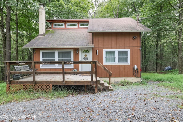 chalet / cabin featuring a shingled roof, a chimney, and a deck