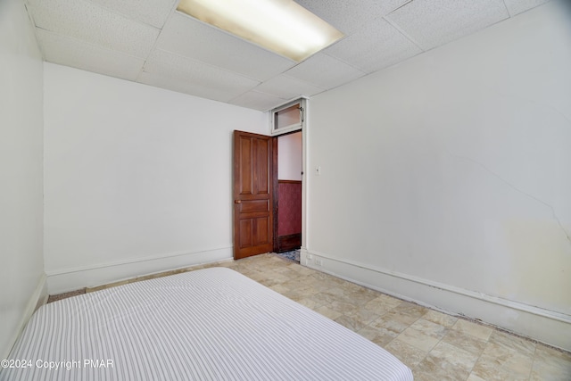 bedroom featuring a paneled ceiling and baseboards