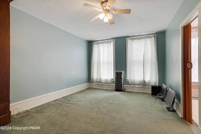 unfurnished room featuring carpet, radiator, ceiling fan, and baseboards