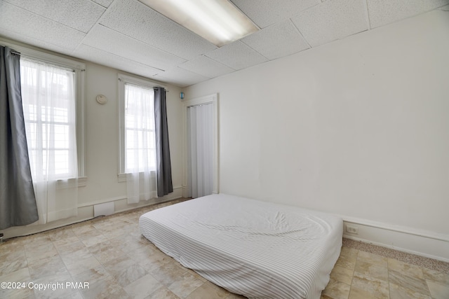 bedroom featuring baseboards and a drop ceiling