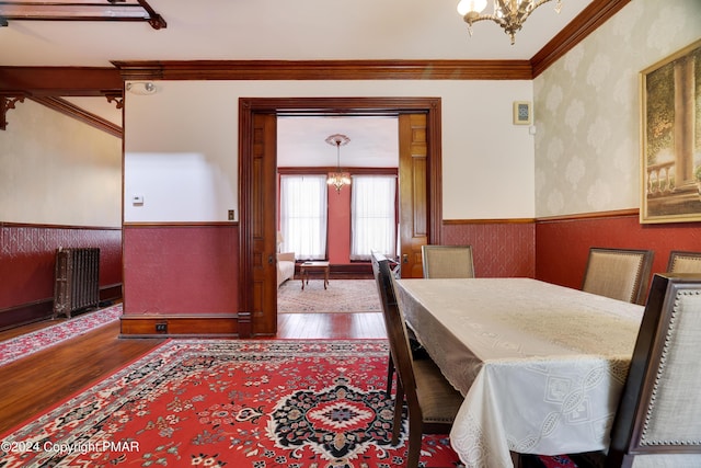 dining area with radiator, wood finished floors, a notable chandelier, and wainscoting