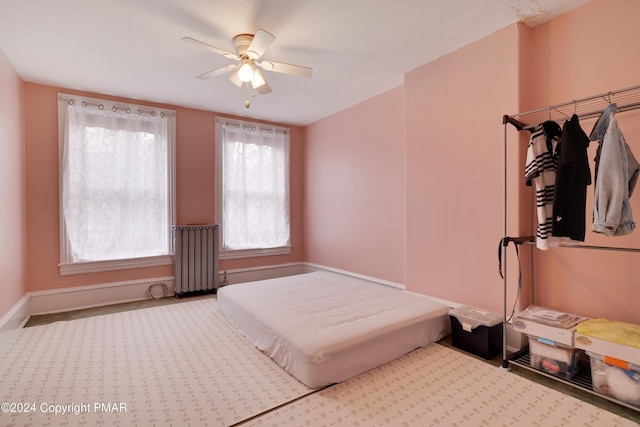 bedroom featuring radiator heating unit, carpet flooring, a ceiling fan, and baseboards