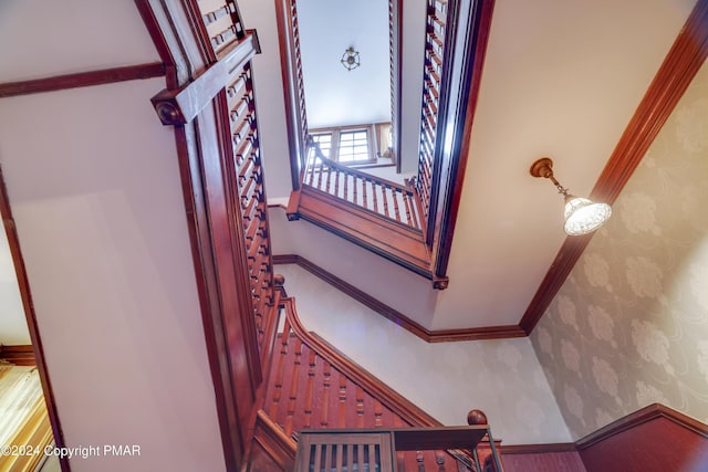 stairs with ornamental molding, baseboards, and wallpapered walls