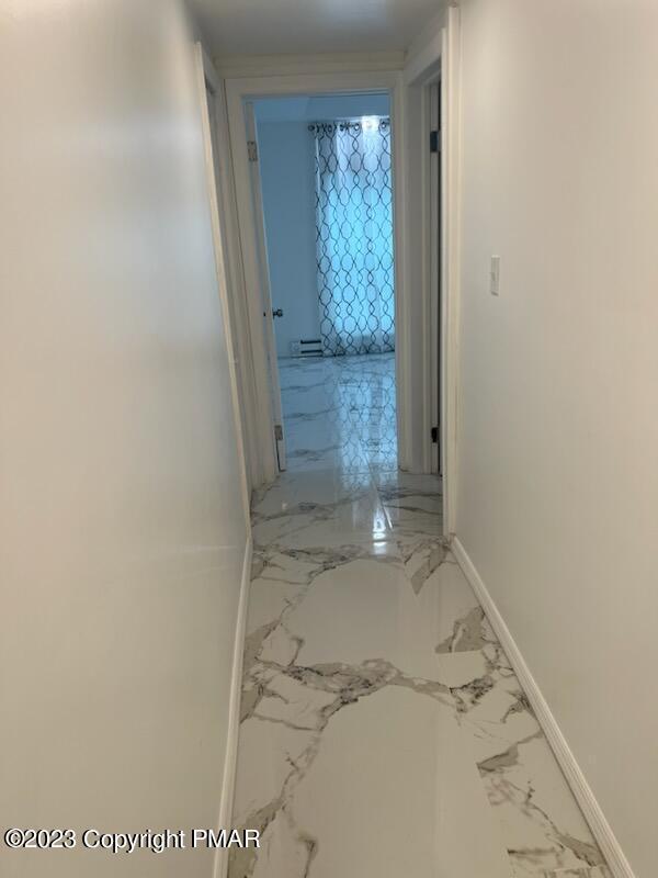 hallway with marble finish floor and baseboards