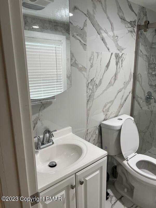 full bathroom with a marble finish shower, marble finish floor, vanity, and toilet