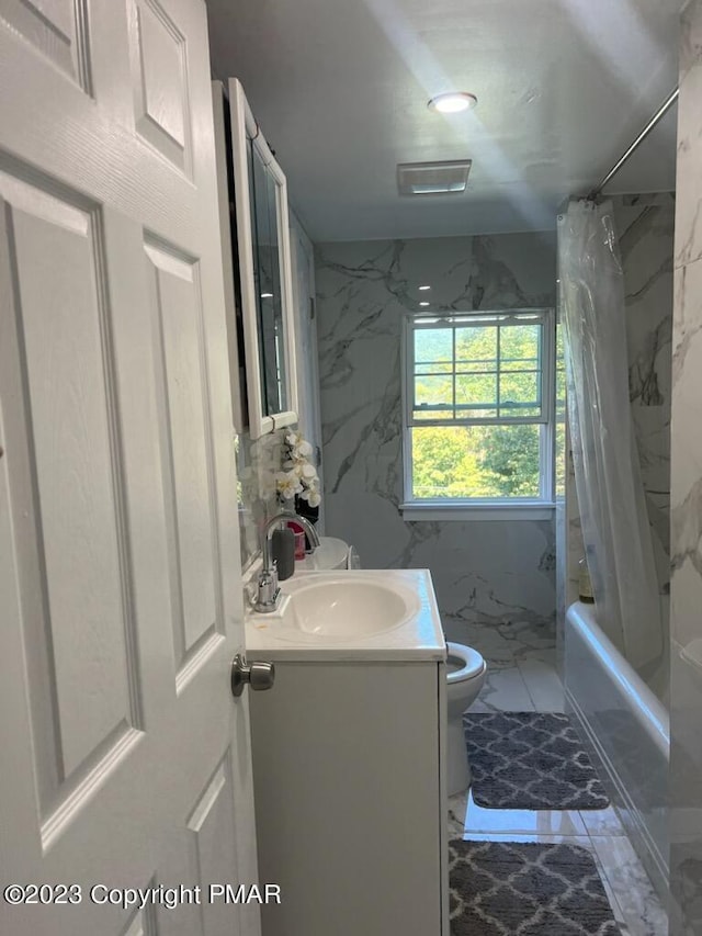 full bath featuring toilet, marble finish floor, shower / bath combo, tile walls, and vanity