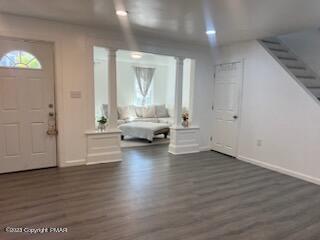 foyer featuring dark wood-style floors, baseboards, and ornate columns