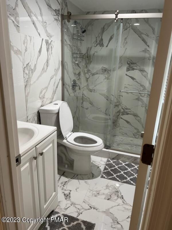 full bathroom featuring vanity, toilet, marble finish floor, and a marble finish shower