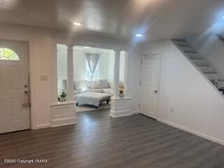 foyer entrance featuring decorative columns, baseboards, dark wood-type flooring, and stairs