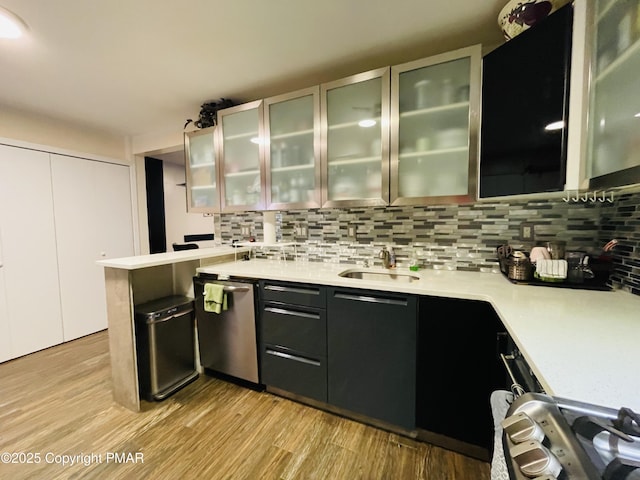 kitchen with a sink, light countertops, backsplash, dishwasher, and glass insert cabinets