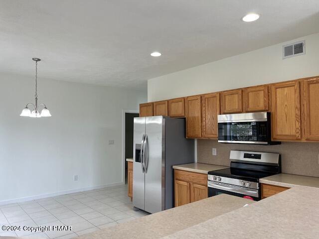 kitchen with light countertops, appliances with stainless steel finishes, brown cabinetry, and visible vents