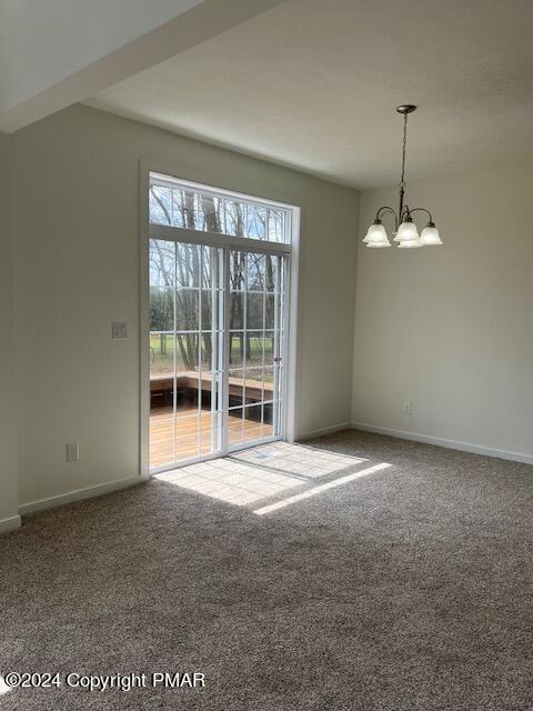 carpeted empty room with baseboards and a chandelier