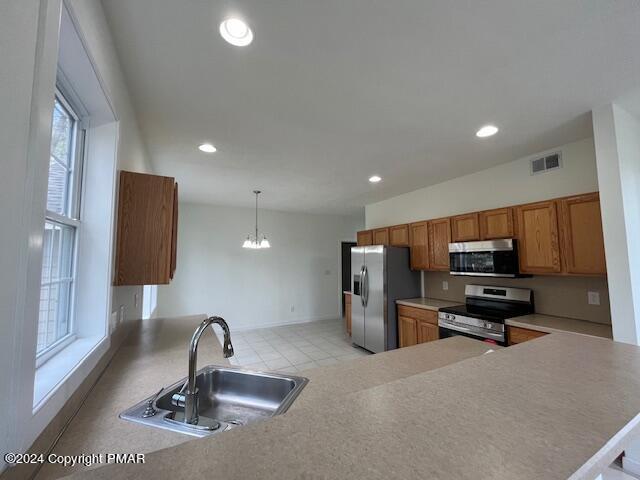 kitchen featuring recessed lighting, stainless steel appliances, a sink, visible vents, and brown cabinets