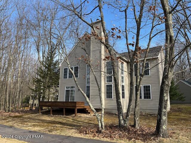 view of side of home with a chimney and a wooden deck