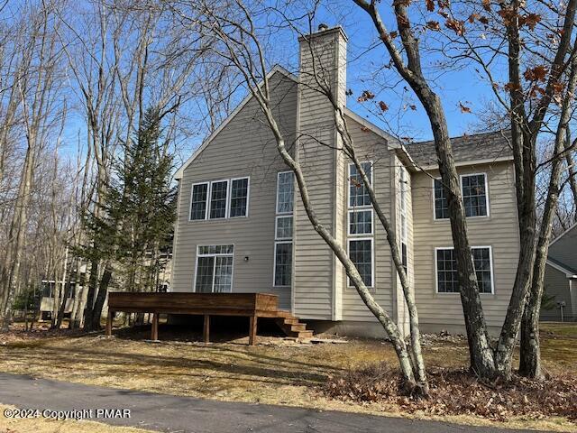 back of property featuring a chimney and a wooden deck