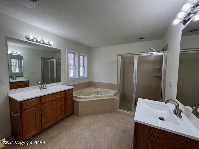 full bath featuring a garden tub, a stall shower, two vanities, and a sink