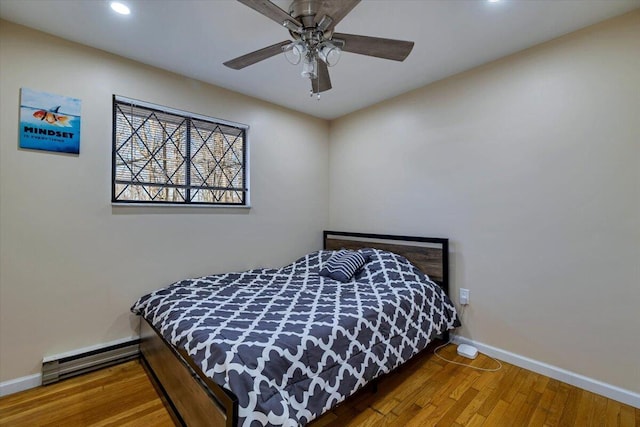 bedroom featuring a ceiling fan, a baseboard heating unit, wood finished floors, recessed lighting, and baseboards