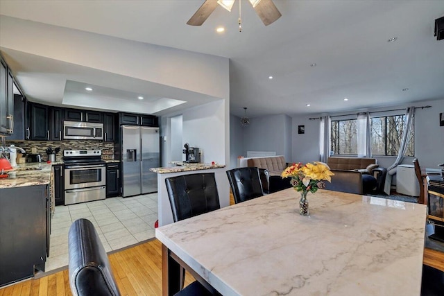 dining area featuring recessed lighting, a tray ceiling, ceiling fan, and light wood-style flooring