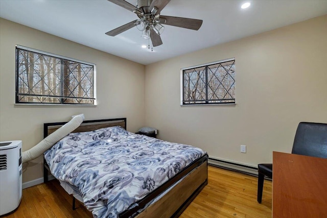 bedroom with wood finished floors, baseboards, a baseboard radiator, recessed lighting, and ceiling fan