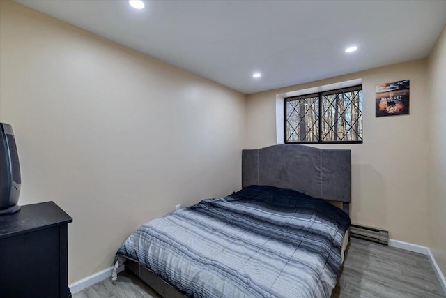 bedroom with recessed lighting, wood finished floors, baseboards, and a baseboard radiator