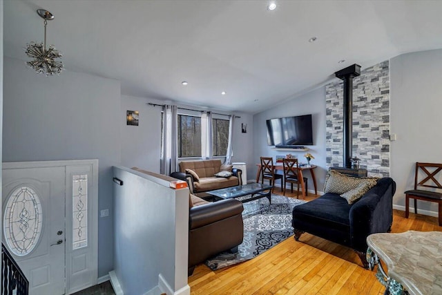 living room with baseboards, wood finished floors, a wood stove, and vaulted ceiling