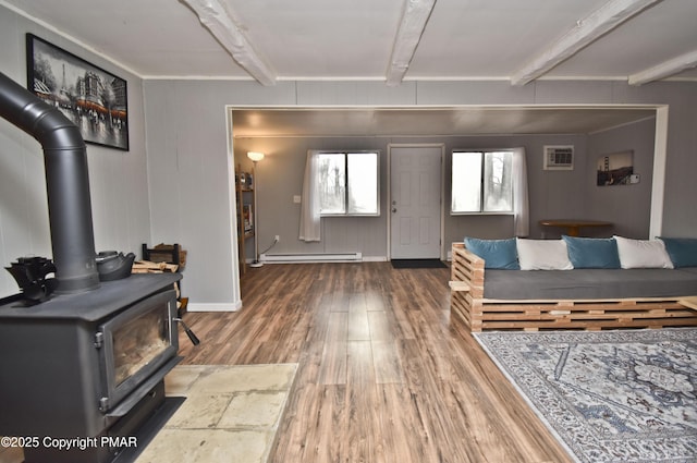 entrance foyer with wood finished floors, an AC wall unit, baseboard heating, beam ceiling, and a wood stove