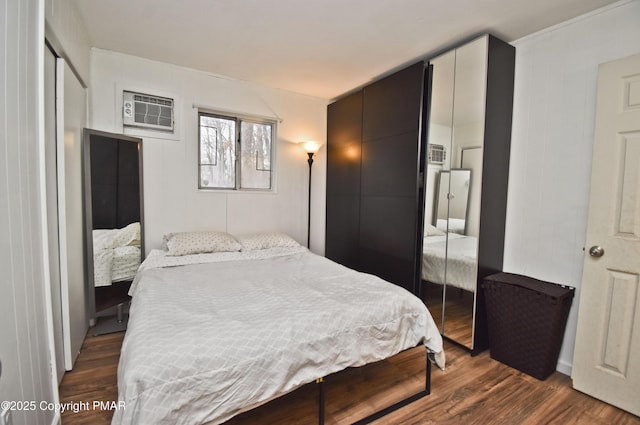 bedroom with dark wood-type flooring, an AC wall unit, and a closet